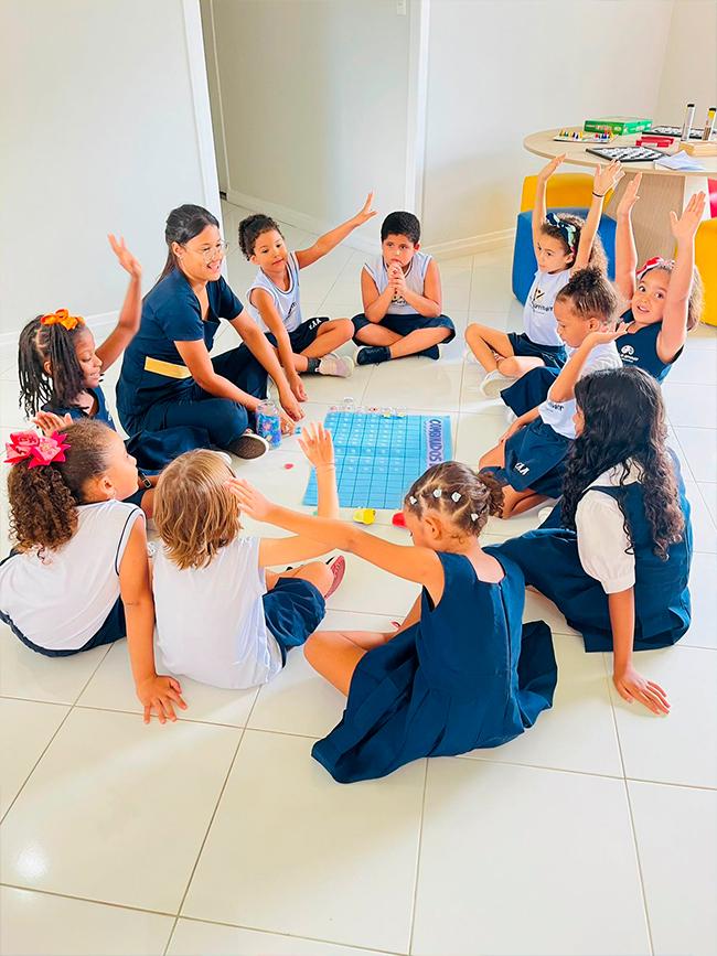 Educadora e alunos dos Anos Iniciais em roda no chão da sala, em atividade de matemática no Colégio Arte de Aprender